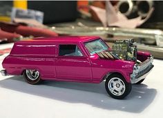 a pink toy truck with its hood open on top of a white table next to other toys