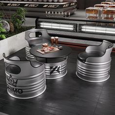 three metal stools sitting on top of a wooden floor next to a table filled with food