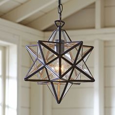 a chandelier hanging from the ceiling in a room with white walls and windows