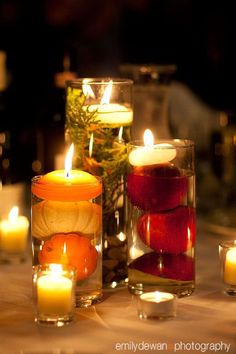 candles are arranged in glass vases on a table