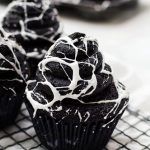 chocolate cupcakes with white icing on a cooling rack