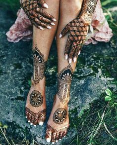 the legs and feet of a woman with henna tattoos on her body, sitting in grass