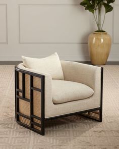 a white chair sitting on top of a rug next to a vase