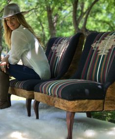 a woman sitting on top of a wooden bench in the woods with her legs crossed