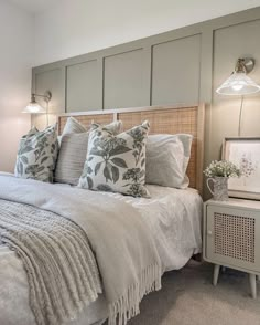 a bed with white linens and pillows in a small room next to a night stand