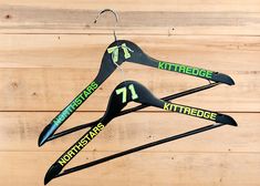 three black hangers with green letters and numbers hanging on wooden planks in the shape of an arrow