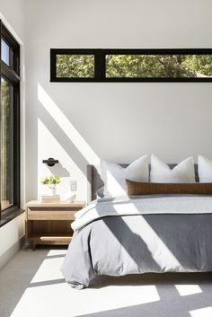 a bedroom with white walls and large windows