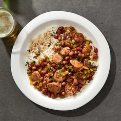 a white plate topped with rice and beans next to a glass filled with beer on top of a table