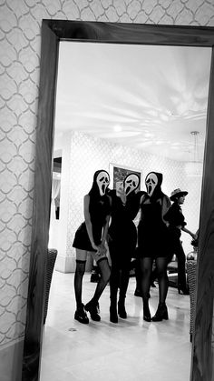 black and white photograph of three women in masks standing next to each other with their arms around one another