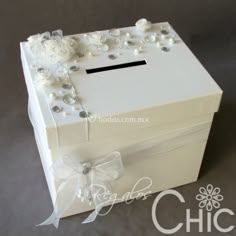 a white box with pearls and bows on the lid is sitting on a gray surface