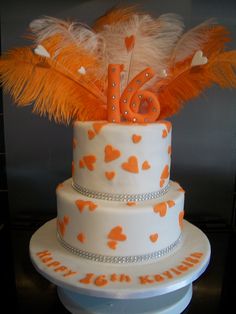 a three tiered cake with orange and white feathers on it's top layer