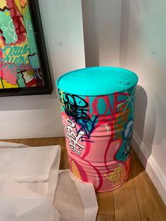 a trash can sitting on the floor next to a painting