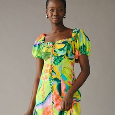 a woman in a colorful dress posing for the camera with her hand on her hip