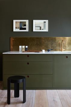 two framed pictures hang on the wall above a kitchen counter with gold leafed accents