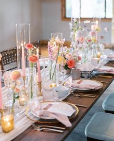 a long table is set with pink and white flowers, candles, plates and napkins