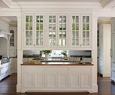 a large kitchen with white cabinets and wood flooring, along with an island in the middle