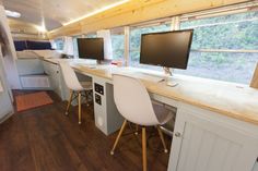 there are two computer screens on the desks in this small home office with wood flooring