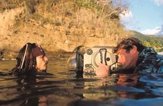 a man and woman in the water with a camera on their head looking at each other