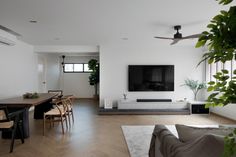 a living room filled with furniture and a flat screen tv mounted on the wall next to a wooden dining table