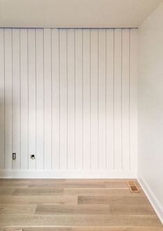 an empty room with white walls and wood flooring on the side, in front of a radiator