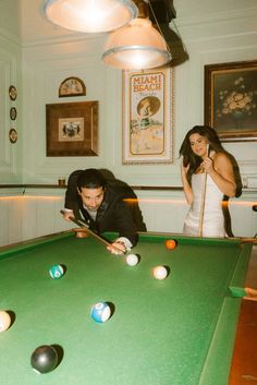 a man and woman playing pool in a room