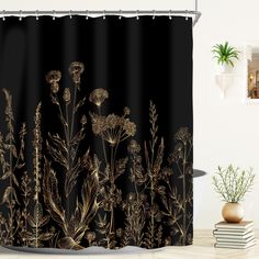 a black shower curtain with gold foil flowers on it and a potted plant in the background