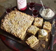 a table topped with desserts and drinks on top of a wooden tray next to a bottle