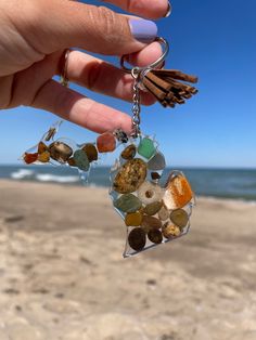 a hand holding a keychain made out of sea glass and seashells