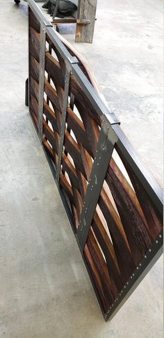 a wooden bench sitting on top of a cement floor next to a metal fence with wood slats