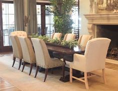 a dining room table with many chairs around it and a fireplace in the back ground