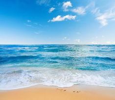 an ocean view with waves crashing on the beach and blue sky in the back ground