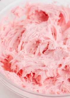 a bowl filled with pink frosting sitting on top of a table