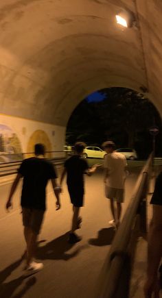 three people are walking in a tunnel with skateboards