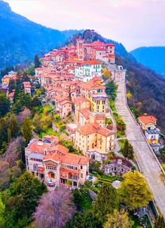 an aerial view of a town on a hill with trees and mountains in the background