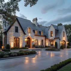 a large white brick house with lots of windows and lights on it's side