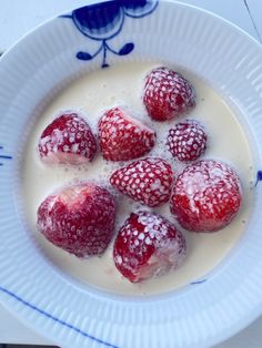 some strawberries are sitting in a bowl of yogurt with powdered sugar on top