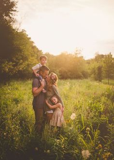 a family poses for a photo in a field with the sun shining down on them