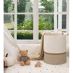 a teddy bear sitting next to a window in a room with white walls and windows