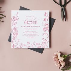 a pink and white wedding shower is on the table next to some flowers, scissors and paper