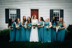 a group of women standing next to each other in front of a white house