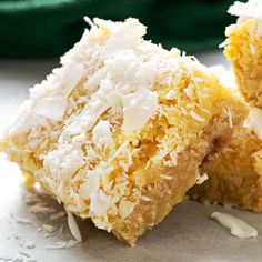 two pieces of coconut cake sitting on top of a white tablecloth next to a green bag