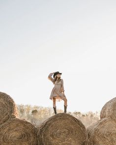 a woman standing on top of hay bales