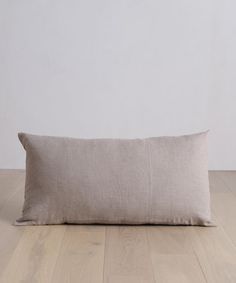 a pillow on the floor in front of a white wall and wooden floors with light colored wood