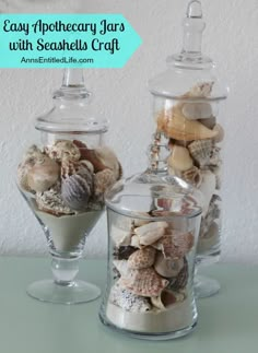 two glass jars filled with seashells on top of a table