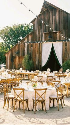 a barn with tables and chairs set up for an outdoor wedding