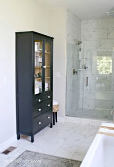 a bathroom with a glass cabinet in the middle and a sink on the other side