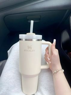 a woman is holding a coffee cup in her car