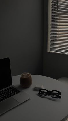 a laptop computer sitting on top of a white table next to a pair of glasses