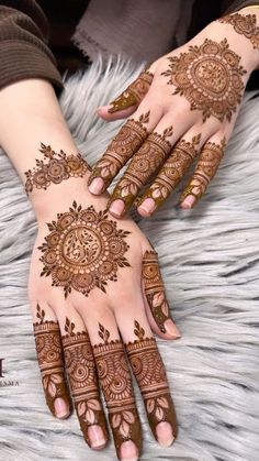 two hands with henna tattoos on them