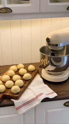 a wooden cutting board sitting on top of a counter next to a mixer and doughnuts